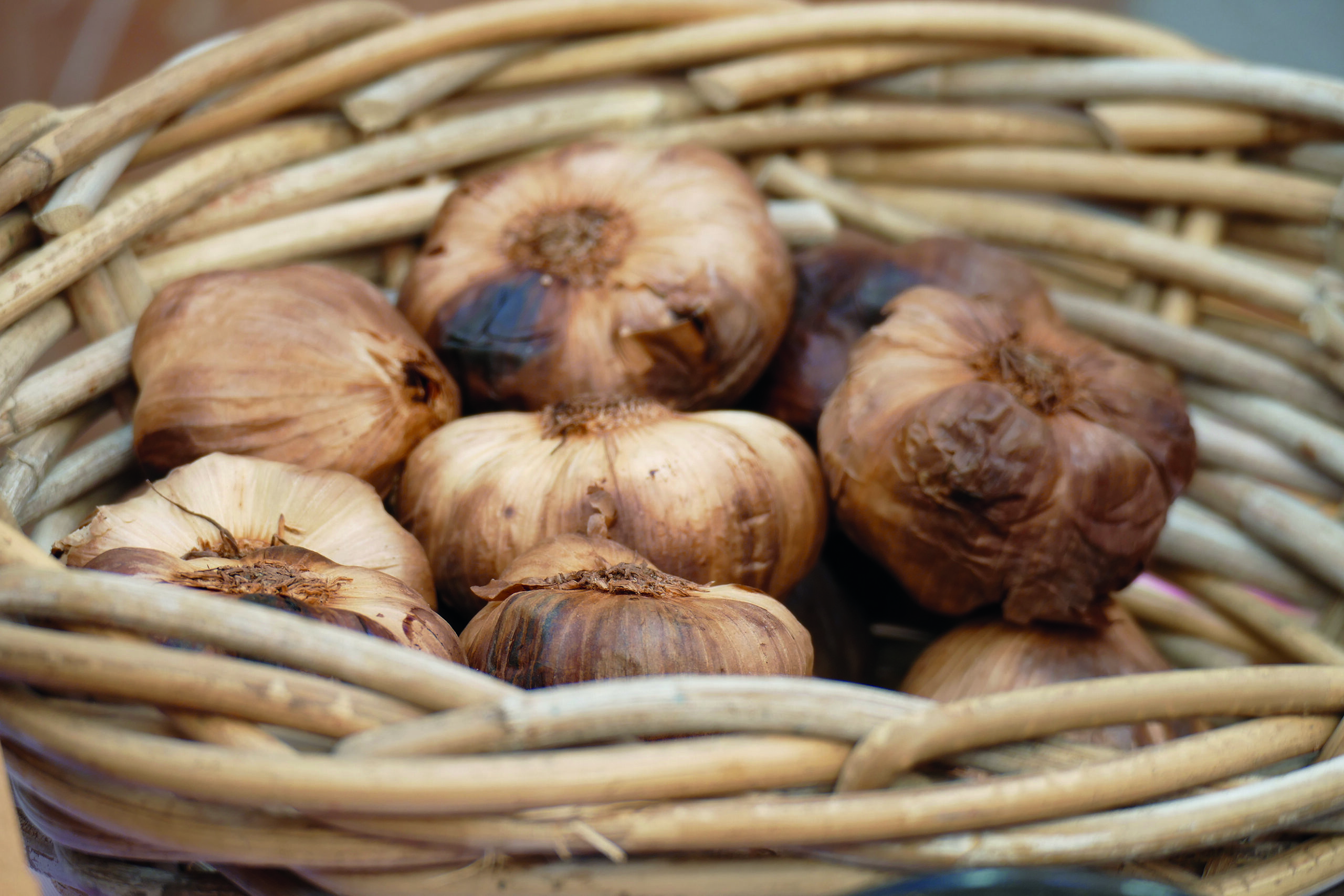A bundle of black garlic in a basket