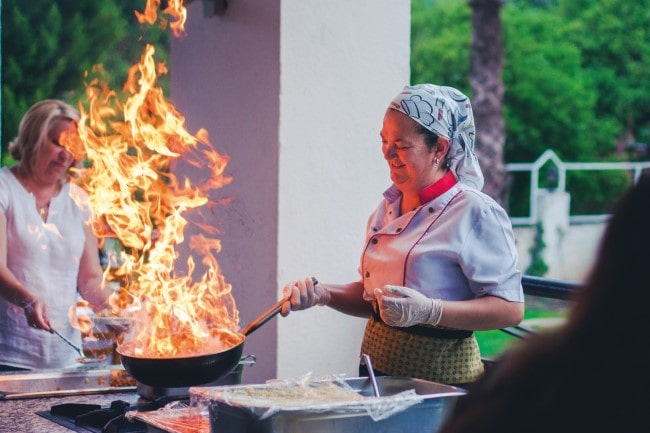 There are a growing number of female role models in professional kitchens today, photo of a lady cooking with fire