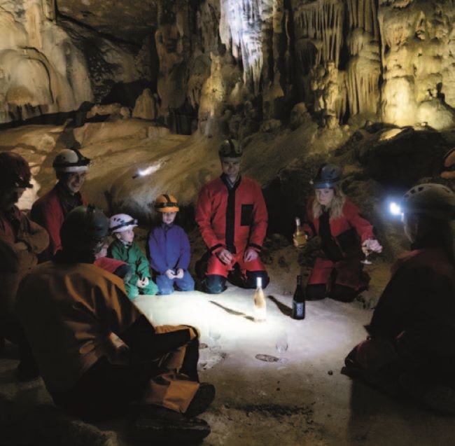 A few people in boiler suits kneeling in Grotte Saint-Marcel